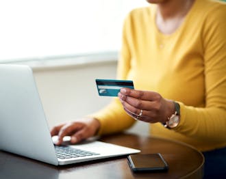 Woman holding credit card near laptop